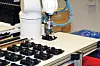 KA Raufoss har fått hjelp av Sintef Manufacturing til å skreddersy automatisert fabrikasjon og montasje. Manifolder flyttet fra matebånd til en mellomstasjon der de blir stilt på skrå. Roboten kan dermed gripe dem uten å blokkere hullene for bremserørskoblingene. Foto: Joachim Seehusen