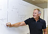 Einar Rasmussen bruker mye tavle og mindre lærebøker i sin undervisning. Her forklarer han hvordan man regner ut forholdet mellom høyden et elektron er skutt ut fra og hvor langt det går. Denne oppgaven kom i årets eksamen for elevene.