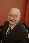 Dr.ing Per Tveit, opprinnerlig fra Voss. Jobbet ved Distriktshøgskolen i Agder, Grimstad. Tatt jan.06, da var han 75 år. Oppfinner av nettverksbuebroen
