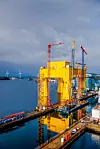 Denne gule 80 meter høye kolossen klargjør Aibel til bruk som HVDC-plattform i tysk del av Nordsjøen. Vindturbinene ved innseilingen til Haugesund i bakgrunnen kan signalisere formålet med byggverket. Foto: Øyvind Sætre