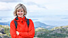 Portrait of happy woman tourist standing smiling outdoors against stunning landscape of Norway