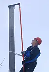 Skrus FAST: Oppfinner Roald Engan (t.h) holder topphetta mens montør Stian Brodersen skrur den fast til stolpen ved hjelp av en drill montert på en lang stang.
