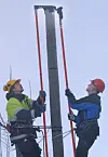 SKRUS FAST: Oppfinner Roald Engan (t.h) holder topphetta mens montør Stian Brodersen skrur den fast til stolpen ved hjelp av en drill montert på en lang stang,