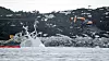 Det pågår arbeider i land rett ved der fregatten KNM Helge Ingstad ligger. En gravemaskin legger på plass sprengmatter oppå fjellet og det er trukket gule tau ut til akterenden av havaristen som så vidt stikker opp av vannet. Foto: Tore Meek / NTB scanpix