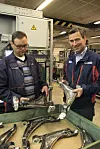 Hans Petter Kristiansen (t.v.) med ferdig montert hjuloppheng til Volvos XC 90-serie. Christopher M. Braathen med delen før den sendes inn i den robotiserte monteringslinjen. Foto: Tore Stensvold