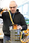 Forsker Giuseppe Guidi med prototypen som er utviklet og testet av Sintef. Den er liten nok til å løftes med én hånd, men fullskala‑versjonen – som skal levere 5 MW – blir et helt annet format: Rundt tre ganger større i fysisk størrelse og over femti ganger tyngre. Foto: Hege Tunstad/Gemini.no