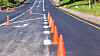 Road painting lines on new asphalt surface with orange markers
