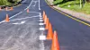 Road painting lines on new asphalt surface with orange markers