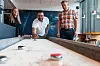 Maren-Elise, Sukhmeet og Hans-Petter tar seg et lite avbrekk med shuffleboard. Foto: TUM Studio