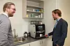 Kaffemaskinen med logo og video i displayet. Magnus Eikens (t.v.) og Morten A. Christophersen morer seg over at det var ett av fjorårets vanskeligste innkjøp. Foto: Tore Stensvold