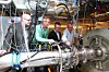 Richard Markeson (Gassco), Morten Løes (Statoil), Harald Fretheim (ABB) og Lars Eirik Bakken (NTNU) i kompressorlabben. Kompressoren sitter i huset til høyre.