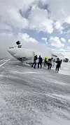 Passasjerer på vei ut av flyet mens en brannbil spyler vann på flyet. Bildet er hentet fra en video innhentet 18. februar 2025. Foto: Peter Koukov/via Reuters/NTB