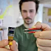 Høy linsetetthet: Oscar Marković holder opp en glassplate som inneholder 4000 mikrolinser laget av et polymer-materiale som deretter er lagt på glasset. Foto: Milan Markovic