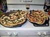 Slik forklarer Googles nettverk dette bildet: Two pizzas sitting on top of a stove top oven.