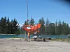 Helikopter henter Ship Arrestor. Kjettingen ligger inne i den oppblåste ringen til venstre. Drivanker, bøye og 'pick up'-utstyr for tauing ligger inne i plastbagen. Finnene sørger for at bagen er lett å ha hengende under helikopteret.