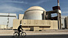 En arbeider sykler forbi atomkraftverket i Bushehr på et bilde fra 2010.