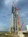 En kran løftet Starship opp på toppen av Super Heavy-raketten sist fredag, og som man kan se, er arbeidet med oppskytningstårnet nesten fullført. Foto: Elon Musk