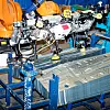 En robot flytter ferdige stålplater frem og tilbake mellom to stabler. Det er en forberedelse til produksjonen av ID og ingeniørene må være sikre på at elektromagnetene plukker med seg kun én plate hver gang, og at den sitter godt. Det måles, justeres, måles på nytt og testes på alle mulige vis. Foto: Joachim Seehusen
