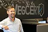 Smilende mann sitter i et kontor foran en VegCERT-logo.