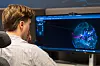 Person foran en dataskjerm med en fargerik visualisering av digitale forbindelser.