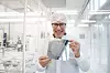 Forsker i renromsutstyr holder en silisiumskive. Han står foran glassvegger og laboratorieutstyr.