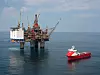 Gullfaks C-plattformen med kraner og et rødt arbeidsfartøy i Nordsjøen.