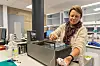 En kvinne håndterer en vannprøve ved en laboratoriebenk.