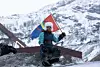 En aksjonist veiver med et samisk flagg ved kobbergurven Nussir ved Repparfjorden under en aksjon fra Natur og Ungdom.