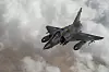 Et fransk Mirage 2000D-fly i lav vinkel over skyer og et tørt landskap.