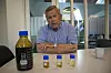 Produktene: Erik Fareid viser fram produktene fra prosessen. I den store flasken til venstre er det pyrolydeoljen slik den kommer ut fra reaktoren. I den neste flasken er den vanlige dieselfraksjonen de produserer etter katalysen og destillering. Den neste flasken er også diesel, men denne har enda bedre kvalitet fordi den har reagert med hydrogen som finnes i pyrolysegassene. Den siste flasken inneholder den aller beste kvaliteten, men her er det tilsatt enda mer hydrogen. Kvaliteten på denne kan sammenliknes med den som kalles HVO. Foto: Odd R. Valmot