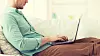 technology, home and lifestyle concept - close up of man working with laptop computer and sitting on sofa at home