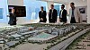 Den norske delegasjonen skuer ut over modellen av Expo 2020. I bakgrunnen teller klokken ned: 108 uker igjen til åpningen.