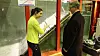 NTNU-stipendiat Priska Helene Hiller forklarer energiminister Terje Søviknes om forskning på plastring av fyllingsdammer (i bakgrunnen) i NTNUs vassdragslaboratorium.