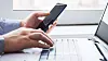 man behind laptop with smartphone in office