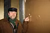 FREDET: Terje Holsen viser hvordan fukt som har trengt inn fra utsiden får gullmalingen i den fredete Tårnbygningen til å flasse av.